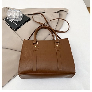 Close-up of brown crocodile pattern PU leather tote bag with elegant gold hardware details