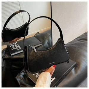 Detail shot of a black vintage baguette bag with pleated texture and silver brand logo