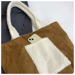 Detail of brown corduroy tote bag with white faux shearling pocket showing phone storage