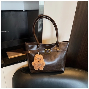 Detailed macro view of dark brown leather tote bag with vintage matte finish and gold buckle