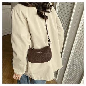 Detail of trendy leopard print crescent bag with Creative Cat text and slim shoulder strap