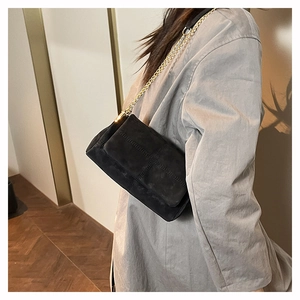 Detail of black suede crossbody bag with gold chain strap and stitching patterns