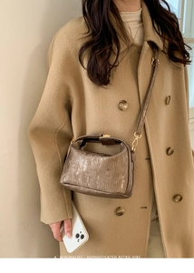 Close-up of minimalist retro pillow bag with metallic bronze texture on model
