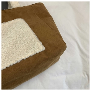 Detailed close-up of brown corduroy and white sherpa patchwork on a winter tote bag