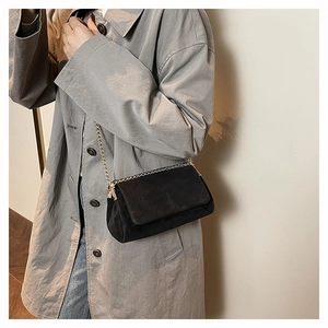 Close-up of black crossbody bag with quilted stitching and gold chain shoulder strap