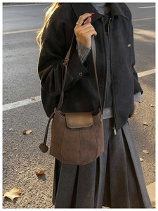 Détail du sac seau en daim marron foncé avec cordon de serrage sur manteau en laine