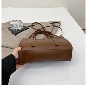 Detail view of dark brown faux crocodile leather handbag with elegant gold hardware
