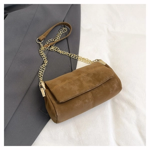 Detail of caramel brown suede bag featuring fine cross-stitching and gold chain strap