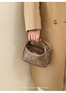 Detail of metallic bronze textured handbag with gold hardware and retro minimalist aesthetic