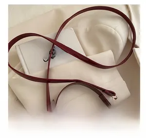 Détail du sac bandoulière en cuir verni bordeaux avec boucles dorées et fine lanière
