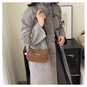 Brown leopard print shoulder bag with Creative Cat text styled on a grey trench coat