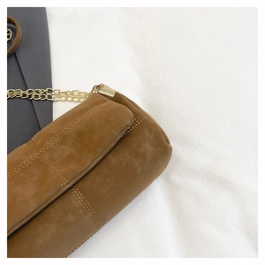Close-up of brown suede tote bag with quilted double stitching and golden metal chain