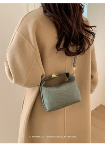 Detail of sage green textured handbag with gold twist lock on camel coat model