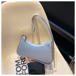 Detail of silver metallic hobo bag with embossed logo on a minimalist white chair