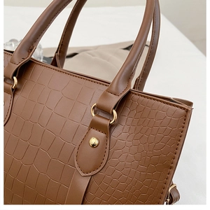 Close-up of brown crocodile texture leather bag with elegant gold metal ring connectors