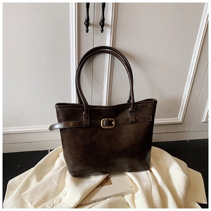 Detail of vintage dark brown tote bag with decorative strap and golden square buckle