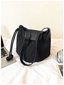 Détail du sac seau noir en suédine avec cordon et breloques sphères dans un décor lifestyle