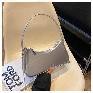 Close-up of silver crescent shoulder bag with metallic wrinkled texture on chair
