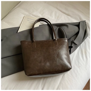 Close-up of minimalist dark brown leather tote bag with fine vintage texture and handles
