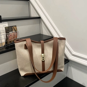 Retro canvas tote bag with brown leather trim and golden buckle on black display stand