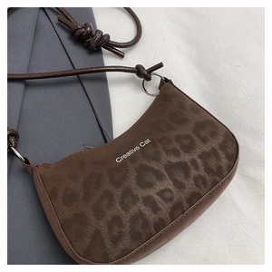 Detail of leopard print underarm bag featuring knotted shoulder strap and Creative Cat logo