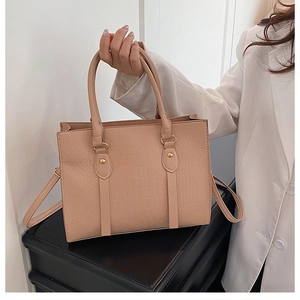 Detail of beige crocodile pattern tote bag with golden hardware and round handles