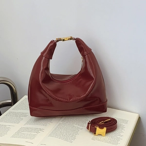 Borsa a luna in vernice rosso scuro con fibbia dorata su libro per stile vintage