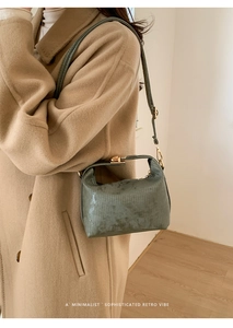 Close-up of olive green square bag with vertical texture and golden twist lock
