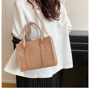 Detail of beige crocodile embossed handbag with gold studs and vertical decorative straps