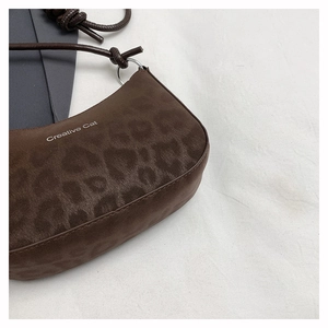 Close-up of leopard print shoulder bag with Creative Cat text and knotted rope strap