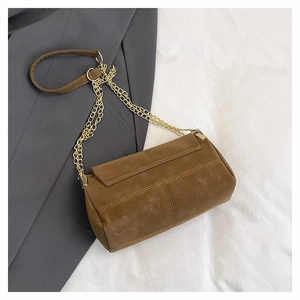 Macro detail of brown matte crossbody bag with chain strap on grey blazer fabric