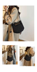 Détail du sac seau noir mat en daim avec pompon décoratif et bandoulière en cuir