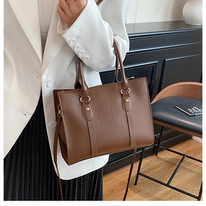Detailed view of dark brown faux crocodile leather tote with handles and long shoulder strap