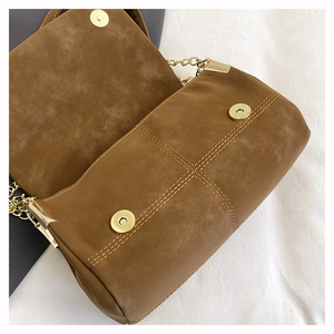 Detail view of brown suede tote bag featuring magnetic closures and gold chain strap