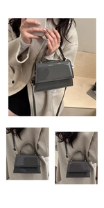 Vue détaillée du sac bandoulière gris foncé en cuir verni avec un manteau beige