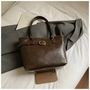 Detail of dark brown vintage leather tote bag showing large capacity and buckle detail