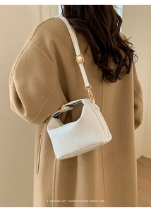 Close-up of a minimalist white leather crossbody bag with premium gold hardware and texture