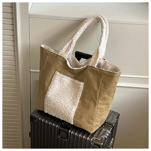 Detail of canvas tote bag with faux fur trim placed on a grey suitcase in a minimal setting