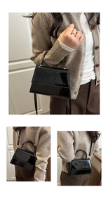 Vue détaillée du sac bandoulière en cuir verni noir avec bandoulière réglable et poignée