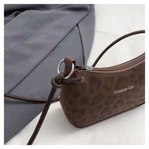 Close-up of leopard print suede shoulder bag with Creative Cat text and silver ring detail