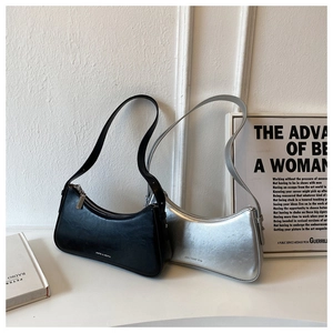 Chic black and silver baguette bags displayed on a minimalist table with artistic props