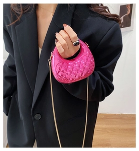 Detail of rose pink quilted mini bag with gold chain strap on a dark blazer