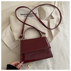 Vue détaillée du sac à bandoulière en cuir verni bordeaux avec finitions en métal doré