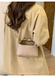 Close-up of khaki retro shoulder bag with minimalist gold lock and fine stripe texture
