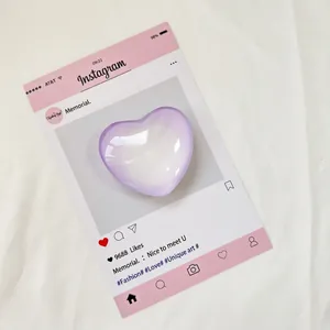 Lavendelfarbener herzförmiger Handy-Griff und goldene strukturierte Ringe auf Rosa