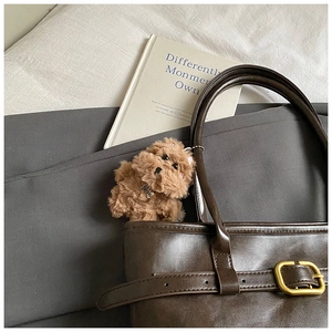 Cute brown plush dog charm with metal Top Dog tag attached to a leather tote bag