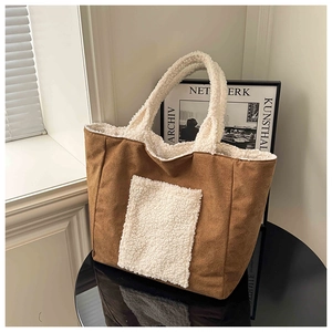 Detail of a brown suede tote bag with white sherpa trim on a minimalist table