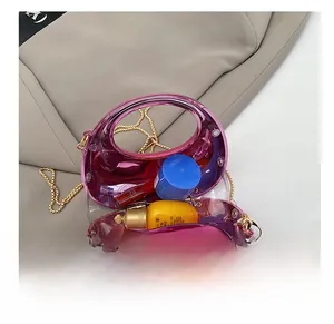 Detail showing internal capacity of pink acrylic mini bag with gold chain and cosmetics