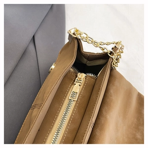 Detail view of brown suede tote bag featuring a gold zipper and chain strap hardware