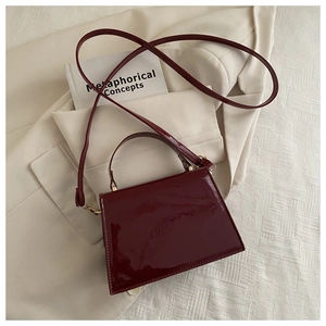 Détail du sac en cuir verni bordeaux montrant la texture lisse et les ferrures dorées